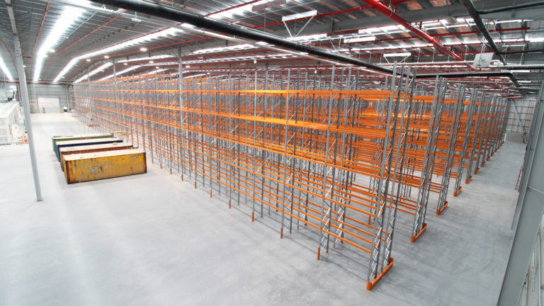 Empty distribution centre in Kemps Creek, NSW prior to installation of Dexion Speedlock pallet racking, showing large clear-span warehouse floor and roof services.